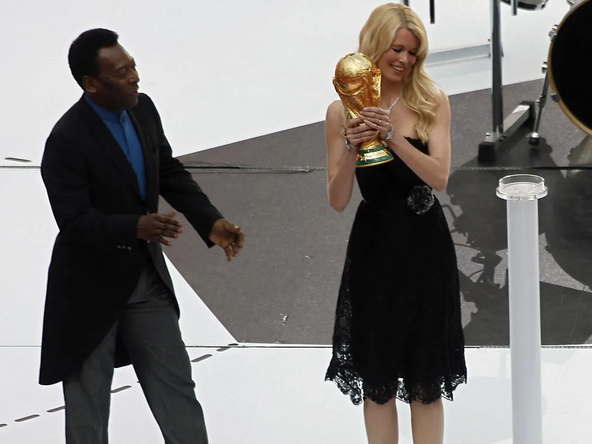 Claudia Schiffer, Brazilian football legend Pele (L) looks on as German supermodel Claudia Schiffer (R) holds the World Cup trophy during opening festivities at Munich's World Cup Stadium ahead of the opening 2006 World Cup match between host Germany and Costa Rica, 09 June 2006. The month-long football extravaganza involving the world's top 32 teams begins in Munich and finishes with the final in Berlin 09 July.            AFP PHOTO / FRANCOIS-XAVIER MARIT (Photo by François-Xavier MARIT / AFP)