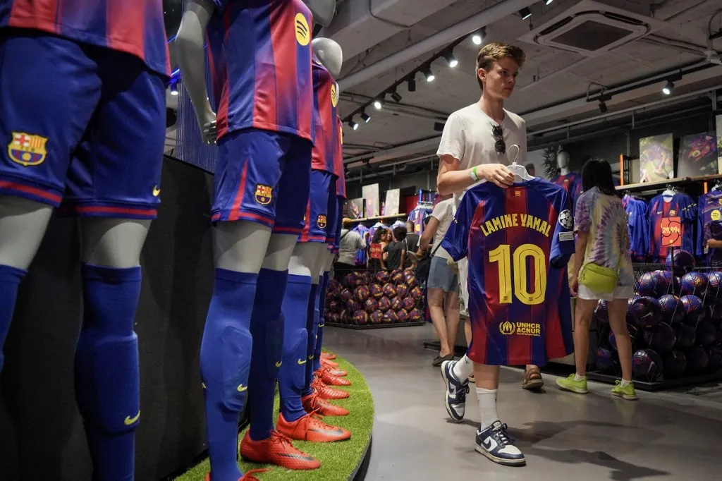 People shop for the new #10 jersey of Barcelona's Spanish forward Lamine Yamal at the official FCB store in Barcelona on July 17, 2025. Yamal, who just turned 18, signed a new contract until 2031 with the Catalan giants after a spectacular season. (Photo by Manaure QUINTERO / AFP)