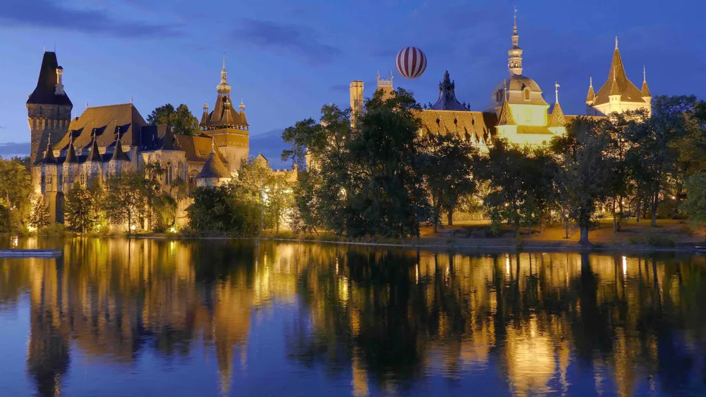 képek a múltból, régi fényképek,   Budapest, 2022. augusztus 8.
Esti kivilágításban a Vajdahunyad-vára (Vajdahunyadvár) épületeinek egy része a Városligeti tó partján. A több hazai építészeti korszak jellegzetes formavilágát megjelenítő épületegyüttes Alp