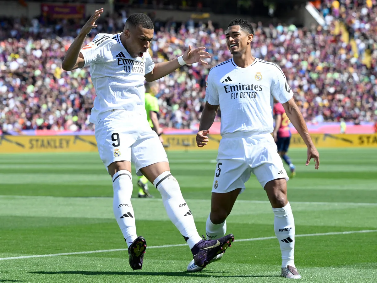 Real Madrid, French forward #09 Kylian Mbappe (L) celebrates with Real Madrid's English midfielder #05 Jude Bellingham after converting a penalty to score their first goal during the Spanish league football match between FC Barcelona and Real Madrid CF at Estadi Olimpic Lluis Companys in Barcelona, on May 11, 2025. (Photo by Josep LAGO / AFP)