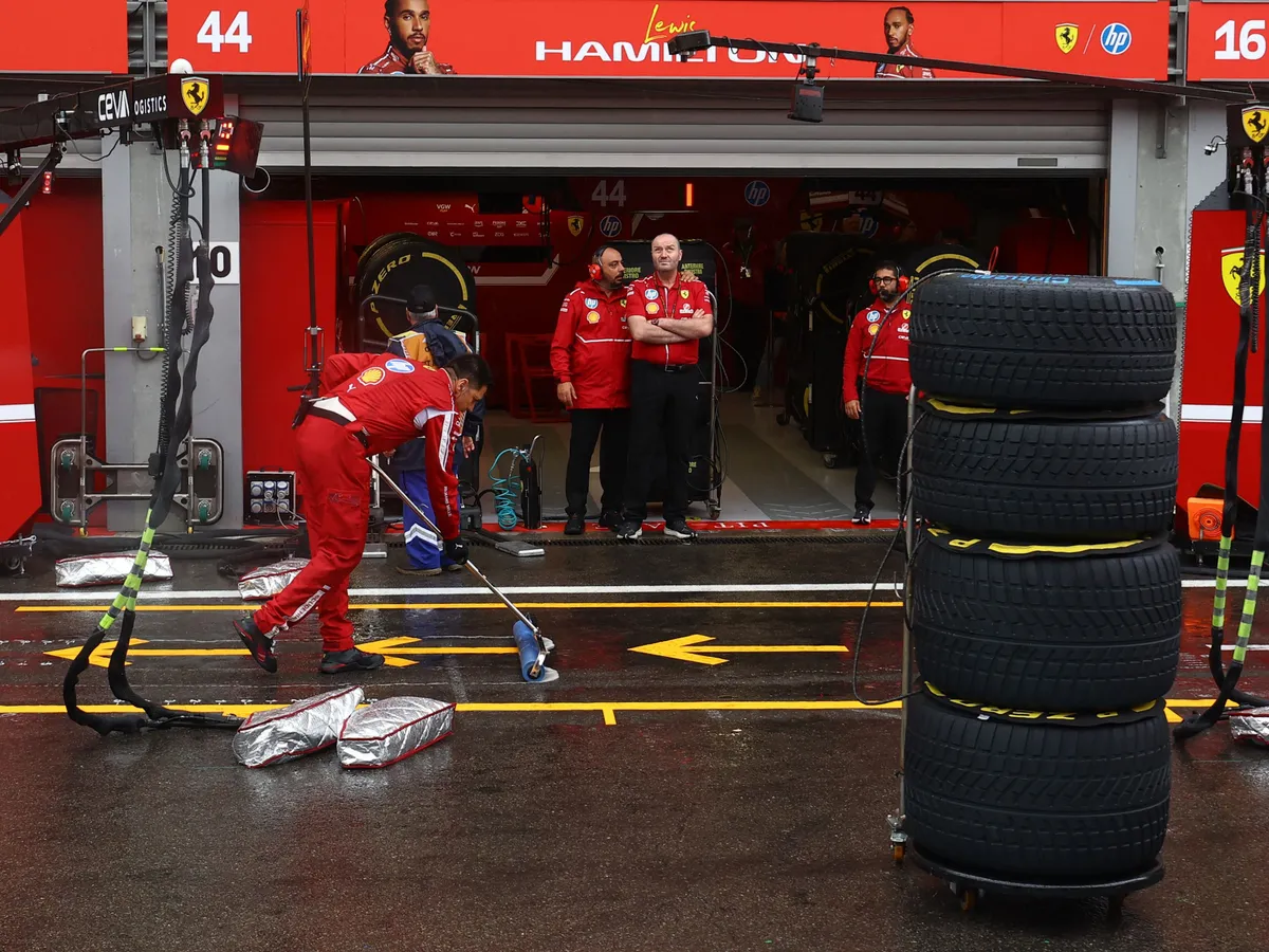 A Ferrari's mechanic dries the pit stop area outside the team's garage after a red flag due to visibility delayed the start of the Formula One Belgian Grand Prix at the Spa-Francorchamps circuit in Spa, on July 27, 2025. (Photo by YVES HERMAN / POOL / AFP)
