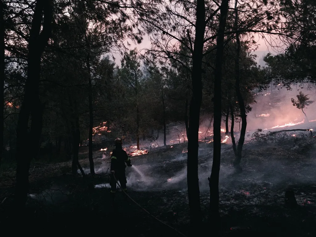 Erdőtűz, Görögország, A firefighter works to extinguish a blaze in a forested area near Asprohori, as wildfires fueled by heat and wind threaten homes in northeastern Attica, in Asprohori, Greece, on July 9, 2025. (Photo by Daniel Yovkov/NurPhoto) (Photo by Daniel Yovkov / NurPhoto via AFP)