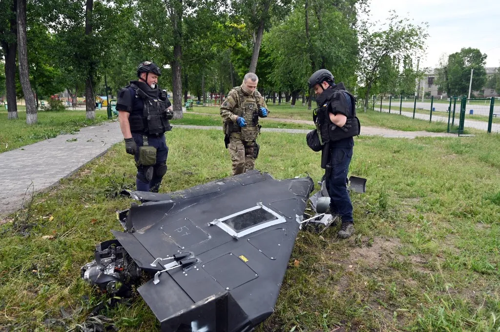 Ukrainian explosives experts and police officers examine parts of a Shahed 136 military drone following an air-attack in Kharkiv on June 4, 2025, amid the Russian invasion of Ukraine. (Photo by SERGEY BOBOK / AFP)