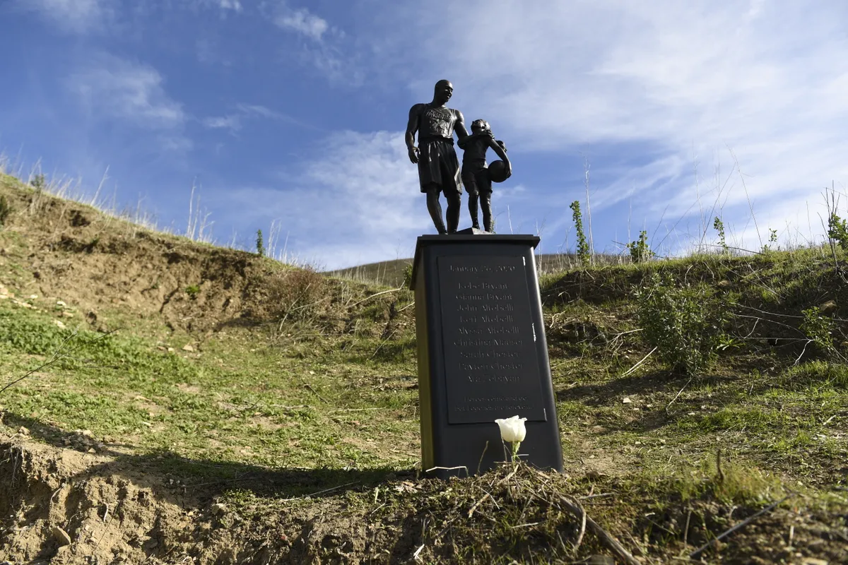 A bronze sculpture by artist Dan Medina, depicting Kobe Bryant, daughter Gianna Bryant, and the names of those who died, is displayed as a one-day temporary memorial at the site of a 2020 helicopter crash in Calabasas, California, on January 26, 2022. Lakers star Kobe Bryant died with his daughter Gianna in a tragic helicopter crash which killed nine people on January 27, 2020. (Photo by Patrick T. FALLON / AFP) / RESTRICTED TO EDITORIAL USE - MANDATORY MENTION OF THE ARTIST UPON PUBLICATION - TO ILLUSTRATE THE EVENT AS SPECIFIED IN THE CAPTION