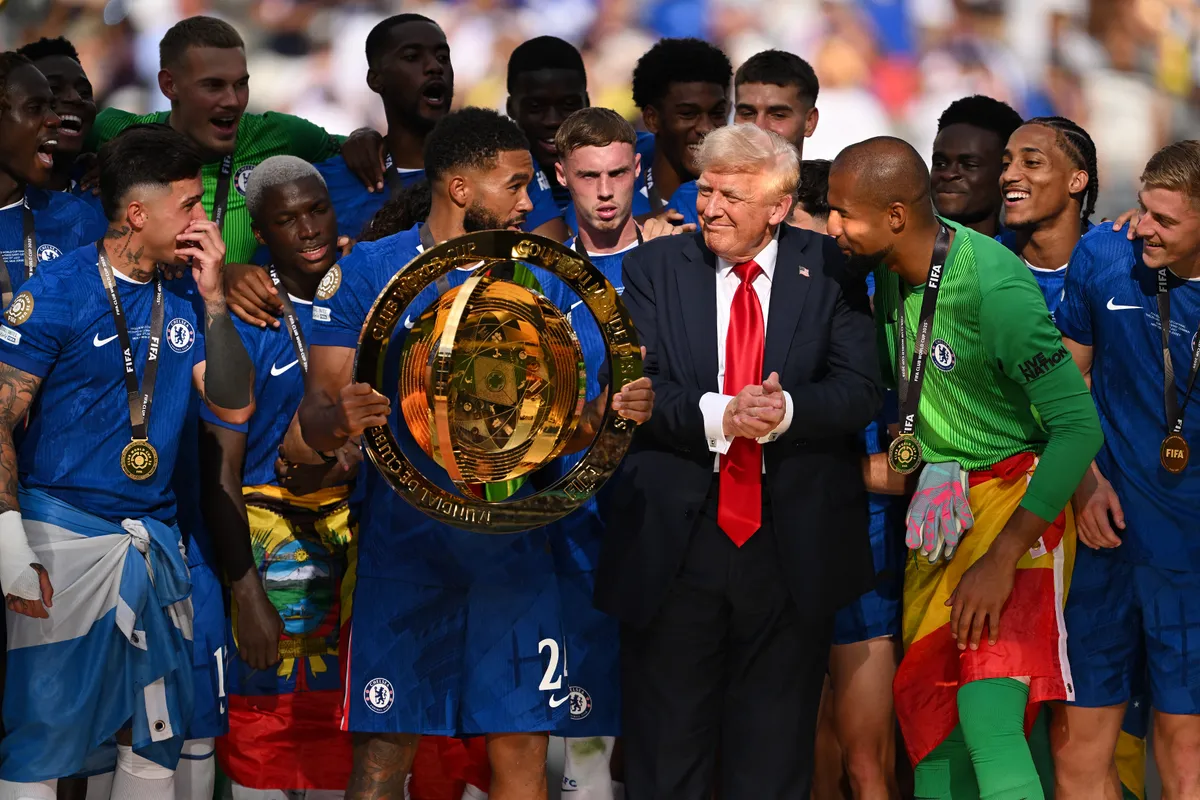 EAST RUTHERFORD, NEW JERSEY - JULY 13: Reece James #24 of Chelsea FC holds the FIFA Club World Cup trophy after their team's victory as U.S. President Donald Trump interacts with Robert Sanchez #1 of Chelsea FC following the FIFA Club World Cup 2025 Final match between Chelsea FC and Paris Saint-Germain at MetLife Stadium on July 13, 2025 in East Rutherford, New Jersey.   David Ramos/Getty Images/AFP (Photo by David Ramos / GETTY IMAGES NORTH AMERICA / Getty Images via AFP)