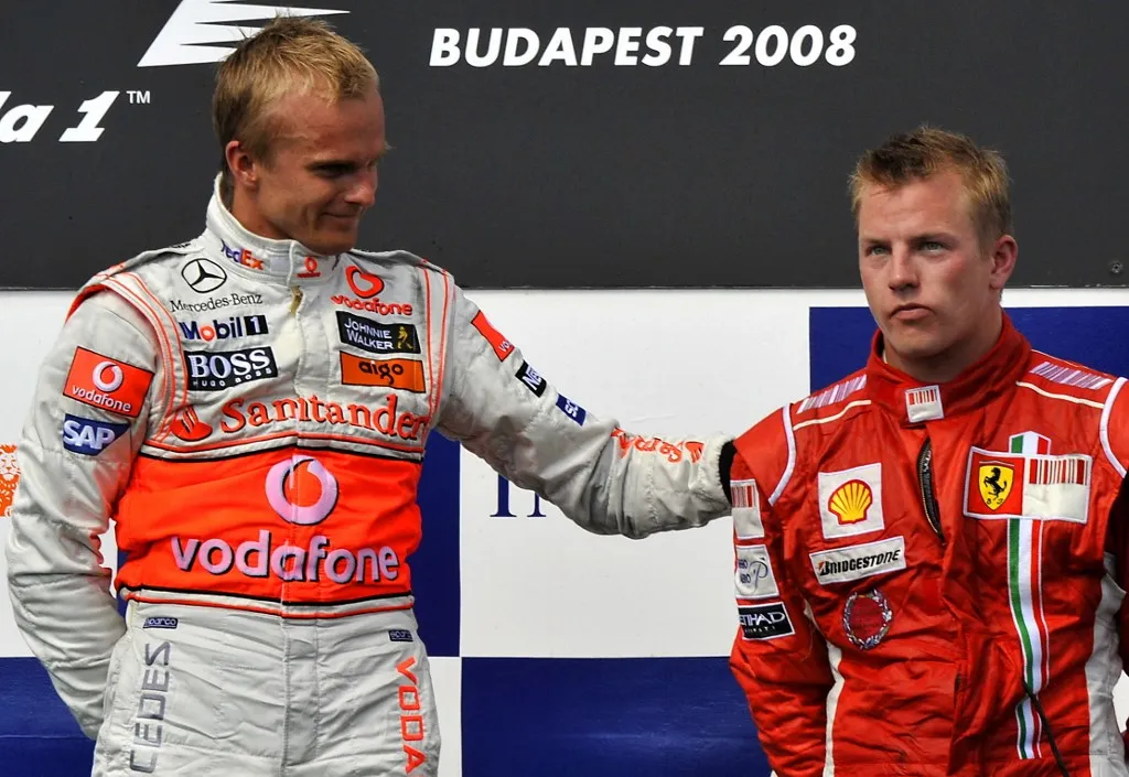 McLaren Mercedes' Finnish driver Heikki Kovalainen (L) commisarates with his compatriot Ferrari's driver Kimi Raikkonen on the podium of the Hungaroring racetrack on August 3, 2008 in Budapest after the Formula One Hungarian Grand Prix. McLaren Mercedes' Finnish driver Heikki Kovalainen won the race ahead of Toyota's German driver Timo Glock and Ferrari's Finnish driver Kimi Raikkonen.      AFP PHOTO / ATTILA KISBENEDEK (Photo by ATTILA KISBENEDEK / AFP)