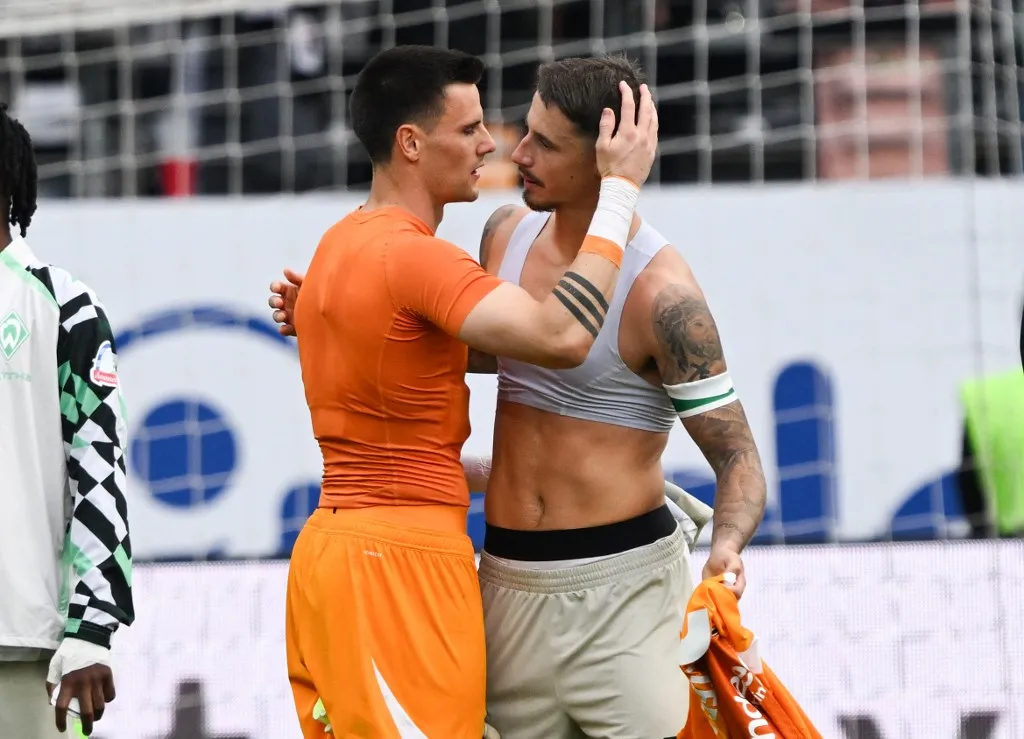 riporternő, 23 August 2025, Hesse, Frankfurt/Main: Soccer: Bundesliga, Eintracht Frankfurt - SV Werder Bremen, Matchday 1, Deutsche Bank Park. Goalkeeper Michael Zetterer (Eintracht Frankfurt, l) comforts Marco Friedl (Werder Bremen) after the match. Photo: Arne Dedert/dpa - IMPORTANT NOTE: In accordance with the regulations of the DFL German Football League and the DFB German Football Association, it is prohibited to utilize or have utilized photographs taken in the stadium and/or of the match in the form of sequential images and/or video-like photo series. (Photo by ARNE DEDERT / dpa Picture-Alliance via AFP)