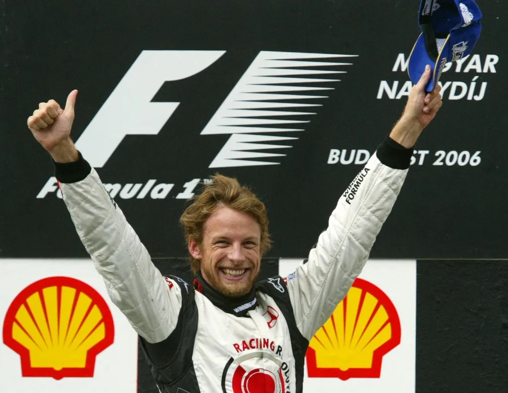 British Honda driver Jenson Button celebrates on the podium of the Hungaroring racetrack after the Hungarian Grand Prix, 06 August 2006, in Budapest. Button won the race ahead of Spanish McLaren-Mercedes driver Pedro de la Rosa and German BMW Sauber driver Nick Heidfeld. AFP PHOTO ATTILA KISBENEDEK (Photo by ATTILA KISBENEDEK / AFP)