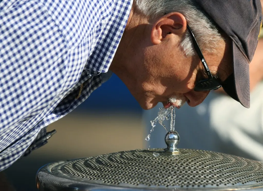 A spectator drinks water from a fountain to cool down at the Australian Open tennis tournament in Melbourne on January 30, 2009.   Melbourne is in the grip of its worst heatwave in a century, with temperatures topping 43 degrees Celsius (109 Fahrenheit) for a third consecutive day,  causing train tracks to buckle and power grids to crash.   AFP PHOTO/Antony DICKSON (Photo by ANTONY DICKSON / AFP)