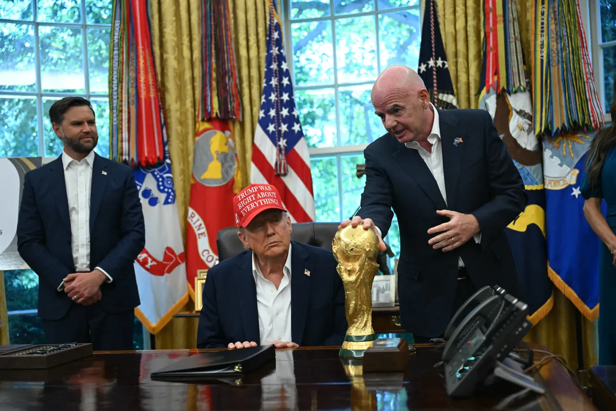 FIFA president Gianni Infantino (R) hands the World Cup Trophy to US President Donald Trump in the Oval Office of the White House in Washington, DC, on August 22, 2025. Also pictured, US Vice President JD Vance (L). Trump announced the 2026 World Cup draw will be held on December 5 at Washington's Kennedy Center. (Photo by ANDREW CABALLERO-REYNOLDS / AFP), foci-vb