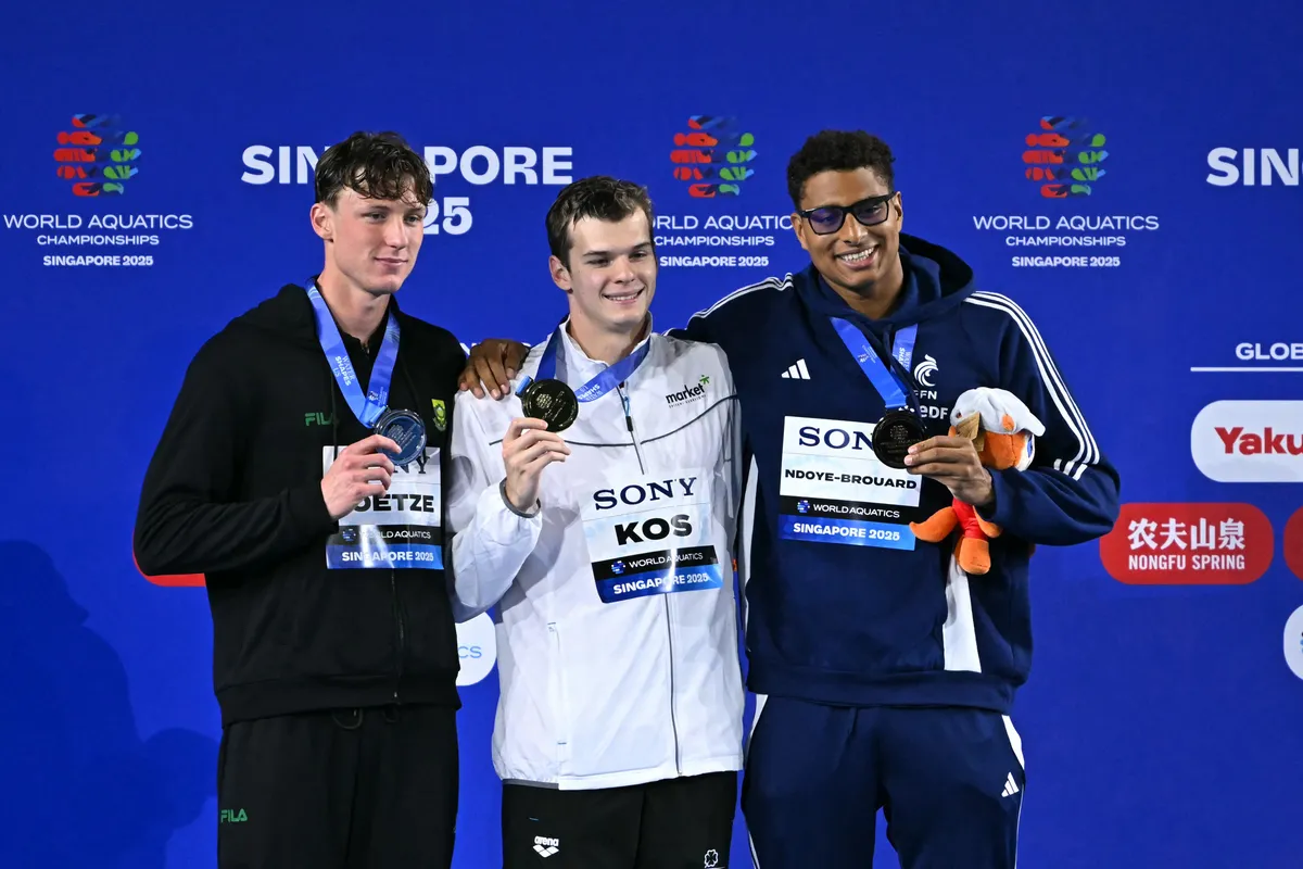 (L-R) Silver medallist South Africa's swimmer Pieter Coetze, gold medallist Hungary's swimmer Hubert Kos and bronze medallist France's swimmer Yohann Ndoye-Brouard celebrate on the podium of the men's 200m backstroke swimming event during the 2025 World Aquatics Championships in Singapore on August 1, 2025. (Photo by MANAN VATSYAYANA / AFP)