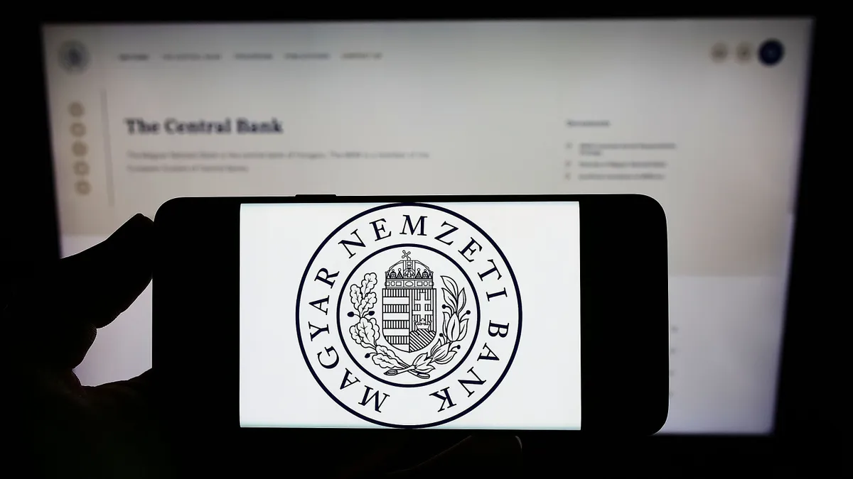 jegybanki előrejelzés, Stuttgart, Germany - 05-22-2022: Person holding smartphone with logo of Hungarian National Bank (Magyar Nemzeti Bank, MNB) on screen in front of website. Focus on phone display. Unmodified photo.