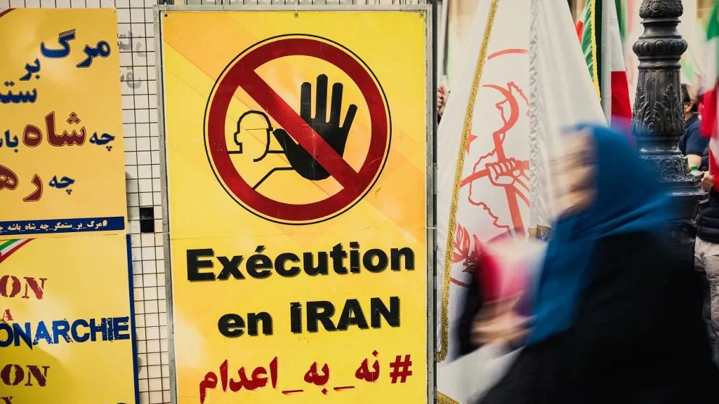 A blurred person and a sign with a stop sign and the words execution en Iran during a rally against executions in Iran in Paris France April 19, 2025. (Photo by Bastien Ohier / Hans Lucas via AFP), Irán