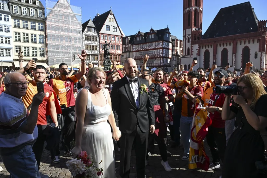 A Galatasaray szurkolói éljeneznek egy ifjú párt, a menyasszony és a vőlegény pedig csatlakoztak a török fanatikusokhoz a frankfurti Romerberg téren