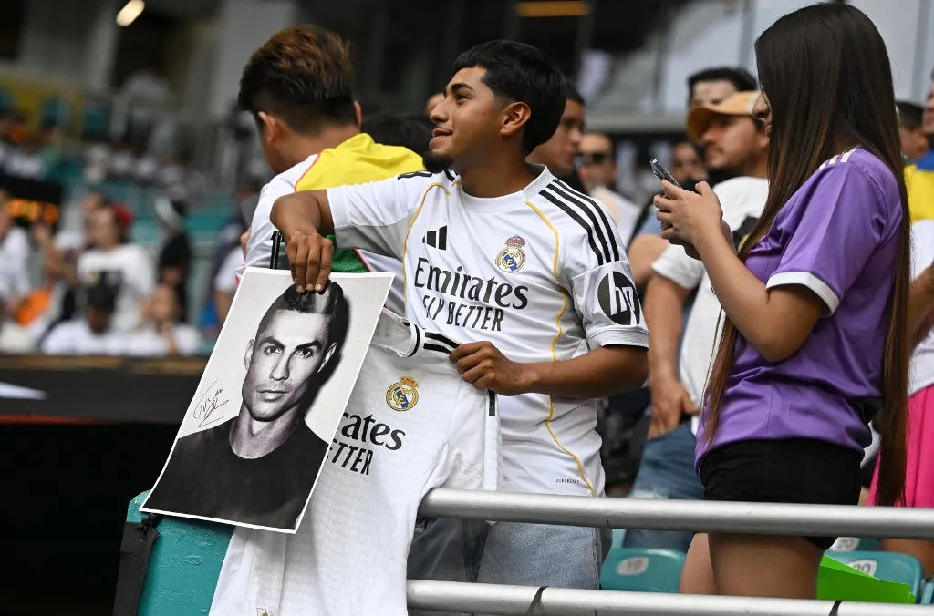 A Real Madrid supporter holds a picture of Portuguese forward Cristiano Ronaldo before the FIFA Club World Cup 2025 round of 16 football match between Spain's Real Madrid and Italy's Juventus at the Hard Rock Stadium in Miami on July 1, 2025. (Photo by PATRICIA DE MELO MOREIRA / AFP)
