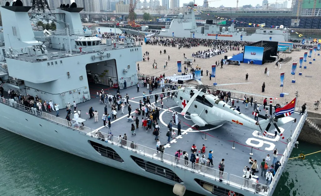 (240422) -- QINGDAO, April 22, 2024 (Xinhua) -- This aerial drone photo shows people visiting supply ship Kekexilihu  (front) at the pier 3 in Qingdao Port of Qingdao, east China's Shandong Province, April 21, 2024. The Chinese People's Liberation Army Navy holds open day events in multiple coastal cities including Qingdao around April 23 to mark the 75th anniversary of its founding.
   From April 20 to 24, the public in Qingdao will be able to tour the missile destroyers Guiyang, Shijiazhuang and Kaifeng, missile frigate Handan, supply ship Kekexilihu, and submarine rescue vessel Hongzehu at the pier 3 and the Qingdao International Sailing Center pier. 
   Most of the vessels have been involved in major missions such as escort mission in the Gulf of Aden, overseas port visits and joint exercises.
   In addition to Qingdao, the navy said it would organize simultaneous open day activities at its barracks in other cities, including Dalian, Yantai, Ningbo, Wuhan, Xiamen, Guangzhou, Haikou and Sanya. (Photo by Ma Jiewen/Xinhua) (Photo by Li Ziheng / Xinhua via AFP)