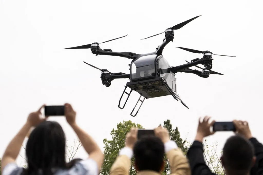 (250327) -- CHANGSHA, March 27, 2025 (Xinhua) -- The air module of XPENG's flying car AEROHT conducts a flight demonstration at Liuye Lake Tourist Resort in Changde City, central China's Hunan Province, March 27, 2025. A ceremony for the flying car's maiden flight in Hunan was held by Chinese electric vehicle maker XPENG here on Thursday.   The flying car consisting of a ground module, an electric vehicle, and an air module, performed the application scenario of cross-water flight on the day. (Xinhua/Chen Sihan) (Photo by Chen Sihan / Xinhua via AFP), Kína