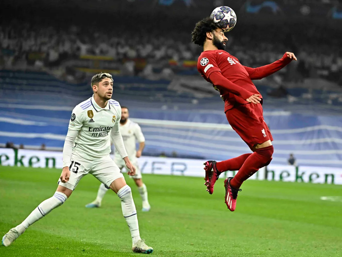 focistafejelés, foci, fejelés,  Real Madrid's Uruguayan midfielder Federico Valverde (L) looks at Liverpool's Egyptian forward Mohamed Salah heading the ball during the UEFA Champions League last 16 second leg football match between Real Madrid CF and Liverpool FC at the Santiago Bernabeu stadium in Madrid on March 15, 2023. (Photo by JAVIER SORIANO / AFP)