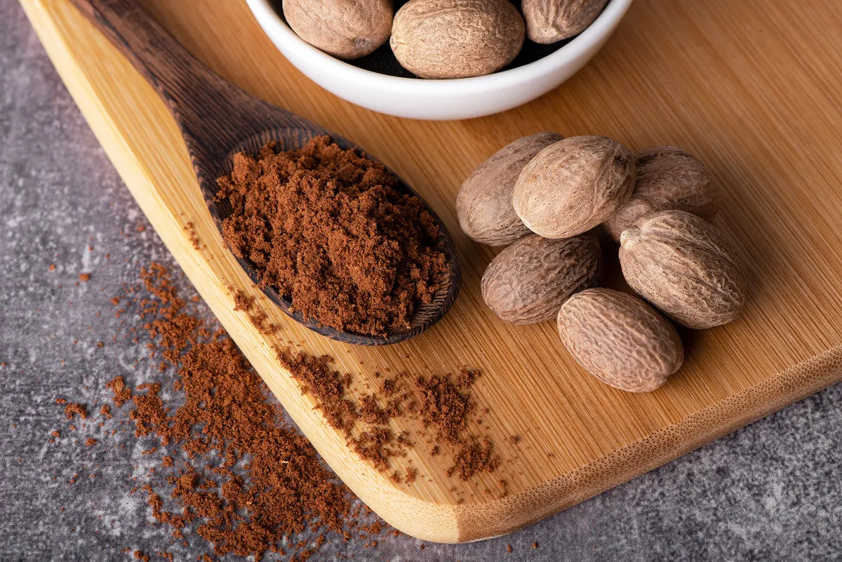 Nutmeg macro in a bowl. Nutmeg powder. Nutmeg spice in a wooden spoon.