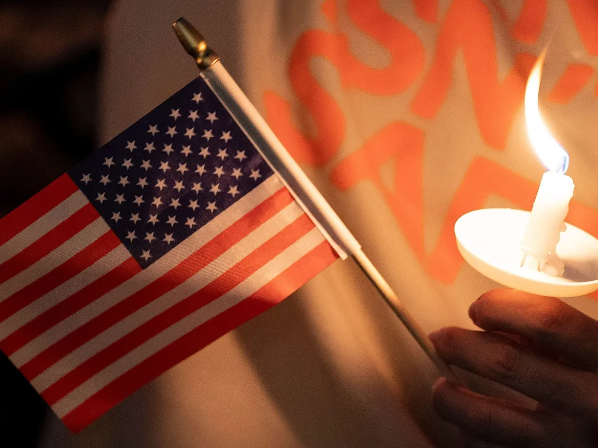 Bayer Zsolt: Mutassuk meg, hogy a normális emberek vannak többen, SEATTLE, WASHINGTON - SEPTEMBER 10: An attendee holds a U.S. flag and a candle during a candlelight vigil and prayer event for Turning Point USA Founder Charlie Kirk on September 10, 2025 in Seattle, Washington. Kirk was shot dead while speaking at Utah Valley University earlier in the day. David Ryder/Getty Images/AFP (Photo by David Ryder / GETTY IMAGES NORTH AMERICA / Getty Images via AFP)