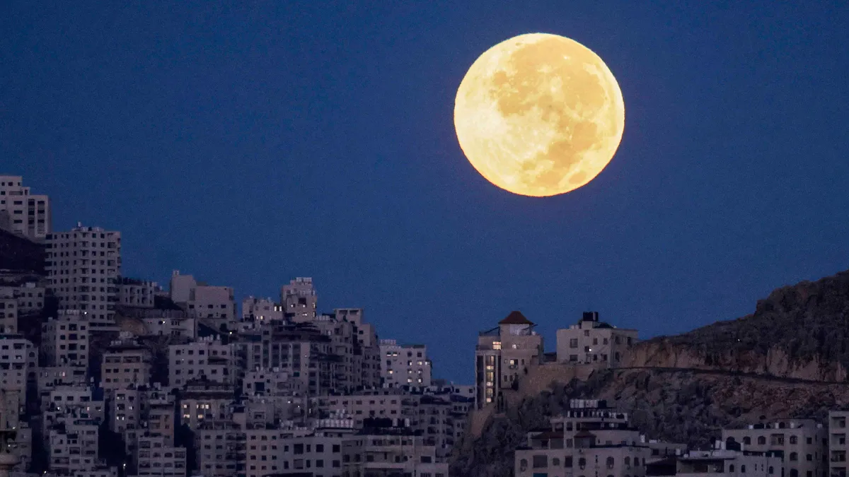 Szuperhold2025, Szuperhold, telihold, hold,   The full moon sets behind Mount Eibal as pictured from Nablus in the occupied West Bank before sunrise early on October 7, 2025. (Photo by Jaafar ASHTIYEH / AFP)