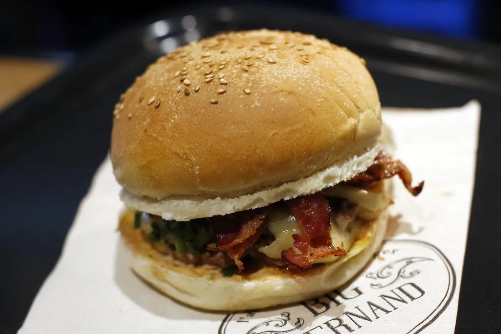 TO GO WITH AFP STORY BY ANNE-SOPHIE MORELA picture taken on March 18, 2015 shows a burger at the "Big Fernand" restaurant in Paris. France has become a new hunting ground for foreign fast food brands looking to establish branches. AFP PHOTO / THOMAS SAMSON (Photo by THOMAS SAMSON / AFP), hamburger