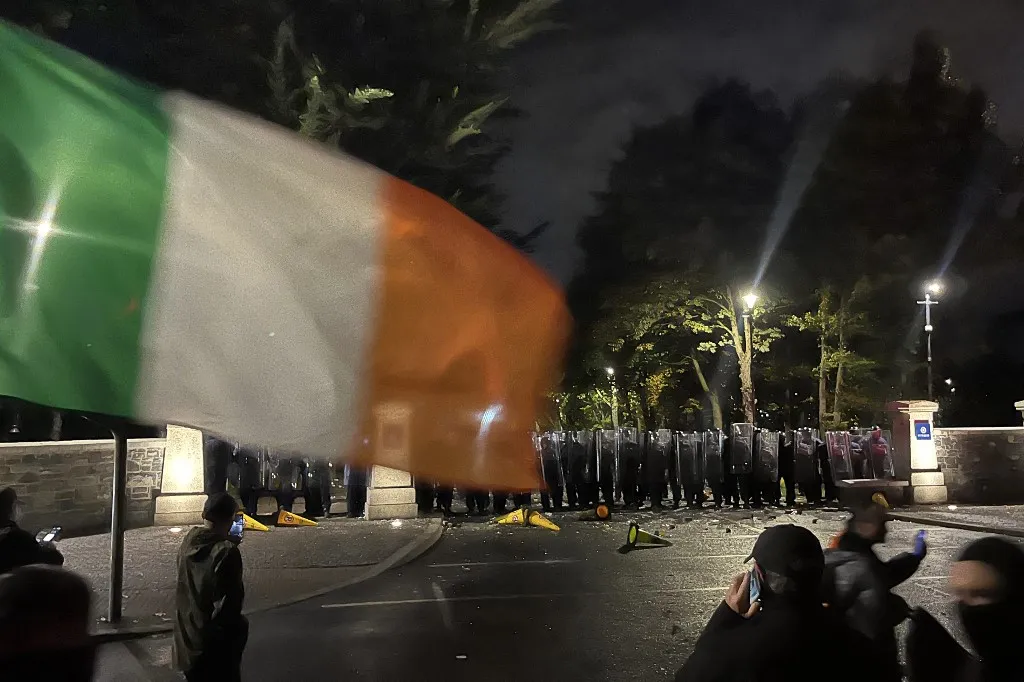 Protesters face a line of police at a demonstration outside a hotel housing asylum seekers in Saggart, south-west of Dublin in Ireland on October 21, 2025. Police in riot gear clashed with at least 500 protesters in Dublin on Tuesday outside an asylum seeker hotel, following allegations that a 10-year-old girl was sexually assaulted. (Photo by Peter MURPHY / AFP)