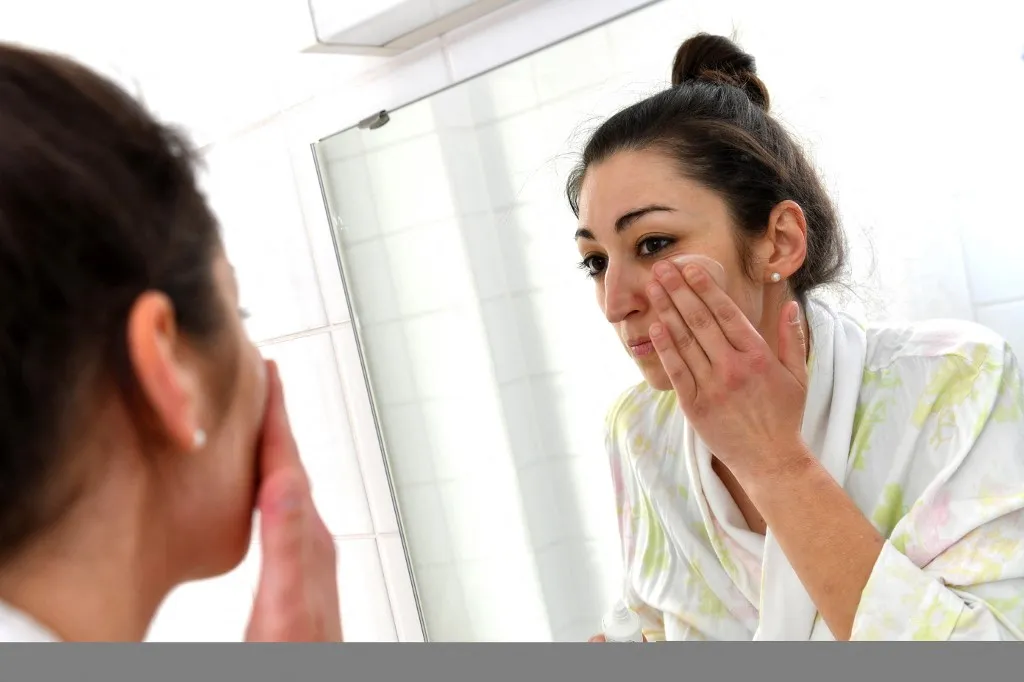 Young woman stands in front of the mirror and removes make-up, remove make-up, cream, apply lotion, make-up, face care, body care, make-up, make-up. Face, Beauty, Beauty Model Released | usage worldwide (Photo by Frank Hoermann/SVEN SIMON / SVEN SIMON / dpa Picture-Alliance via AFP)