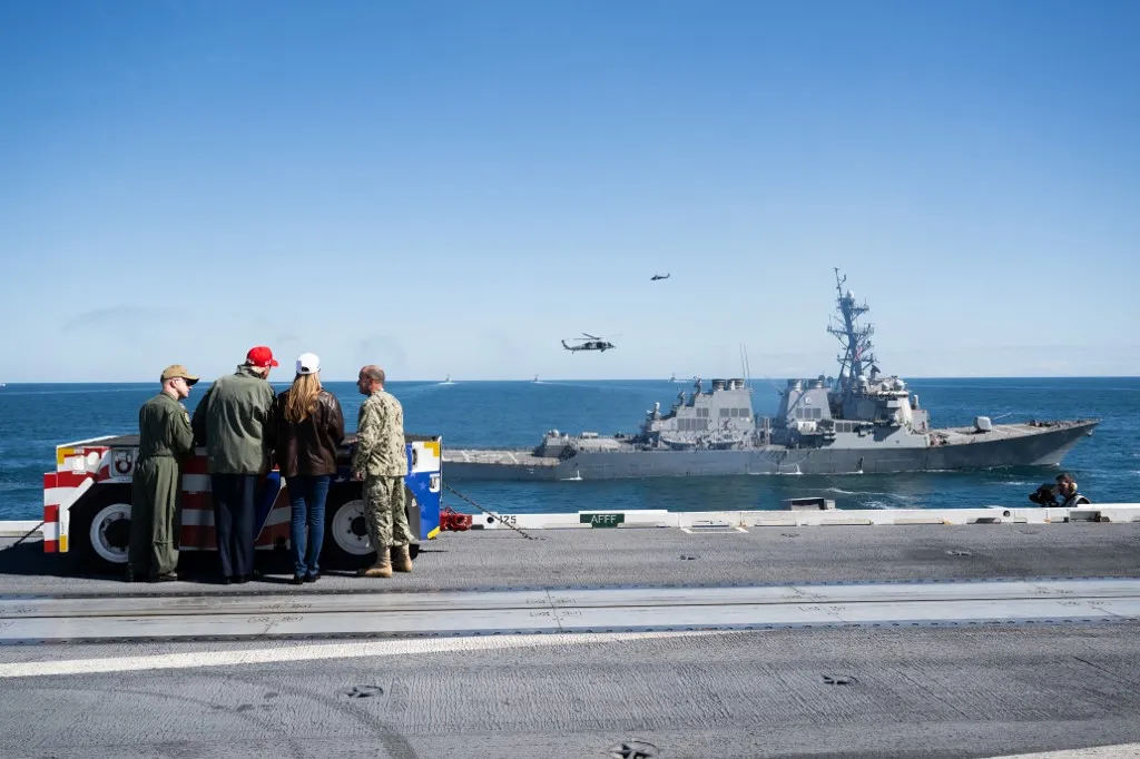 US President Donald Trump and First Lady Melania Trump watch a naval demonstration during a visit to the USS George H.W. Bush aircraft carrier which is out at sea near Norfolk, Virginia, October 5, 2025, as they travel to see a Naval demonstration as part of the US Navy's 250th anniversary celebration, "America's Navy 250: Titans of the Sea - A Salute to the Fleet". (Photo by SAUL LOEB / AFP)