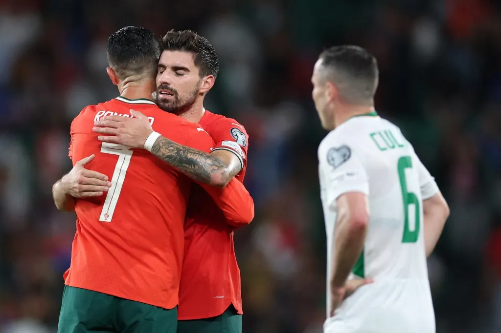 Portugal's forward #16 Cristiano Ronaldo and Portugal's midfielder #21 Ruben Neves (C) hug each other at the end of the 2026 World Cup qualifier Europe zone group F football match between Portugal and Ireland at Jose Alvalade stadium in Lisbon on October 11, 2025. (Photo by PATRICIA DE MELO MOREIRA / AFP) / The erroneous mention[s] appearing in the metadata of this photo by PATRICIA DE MELO MOREIRA has been modified in AFP systems in the following manner: [Ruben Neves] instead of [Ruben Nieves]. Please immediately remove the erroneous mention[s] from all your online services and delete it (them) from your servers. If you have been authorized by AFP to distribute it (them) to third parties, please ensure that the same actions are carried out by them. Failure to promptly comply with these instructions will entail liability on your part for any continued or post notification usage. Therefore we thank you very much for all your attention and prompt action. We are sorry for the inconvenience this notification may cause and remain at your disposal for any further information you may require.