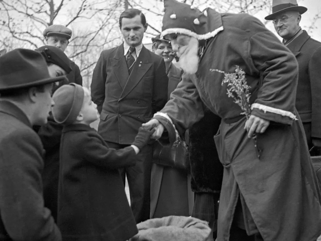 karácsonyivásár, karácsonyi vásár,
A little boy and Santa Claus shaking hands at the christmas market, Germany 1930s. (Photo by Heinz Pollmann / United Archives/Pollmann / mauritius images via AFP)