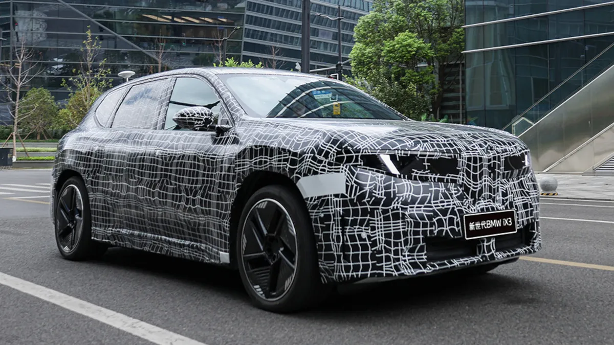 A BMW iX3 L álcázott prototípusa halad az utcán.