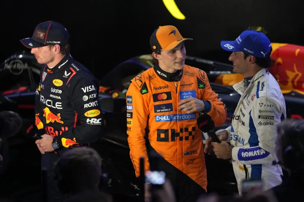 Red Bull Racing's Dutch driver Max Verstappen (L), McLaren's Australian driver Oscar Piastri, (C) and Williams' Spanish driver Carlos Sainz give a pre podium interview after the Formula One Qatar Grand Prix at the Lusail International Circuit in Lusail on November 30, 2025. (Photo by Altaf Qadri / POOL / AFP)
