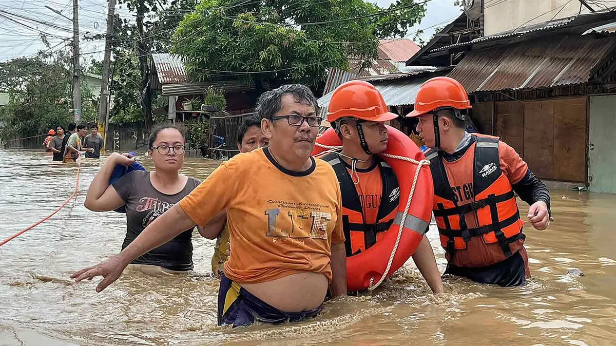This handout photo taken and released on November 4, 2025 by the Philippine Coast Guard (PCG) shows coast guard personnel evacuating people from their flooded homes following heavy rains brought about by Typhoon Kalmaegi in Cebu province, central Philippines. Residents sought refuge on rooftops and cars floated through flooded streets on November 4 as Typhoon Kalmaegi battered the central Philippines, leaving at least two people dead. (Photo by Handout / Philippine Coast Guard (PCG) / AFP) / RESTRICTED TO EDITORIAL USE - MANDATORY CREDIT "AFP PHOTO / PHILIPPINE COAST GUARD (PCG)" - HANDOUT - NO MARKETING NO ADVERTISING CAMPAIGNS - DISTRIBUTED AS A SERVICE TO CLIENTS