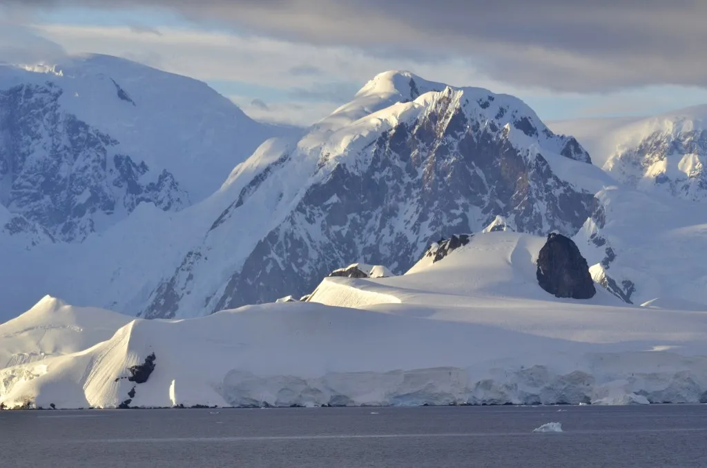 Az Antarktiszi jégtakaró hatalmas hegyvonulatai és gleccserei a tengerpart mentén, ahol a jég olvadása lassan átalakítja a tájat.