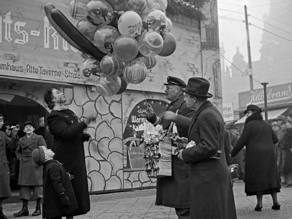 karácsonyivásár, karácsonyi vásár,
A little boy with his mother standing by a balloon seller at the entrance of the christmas market, Germany 1930s. (Photo by Heinz Pollmann / United Archives/Pollmann / mauritius images via AFP)