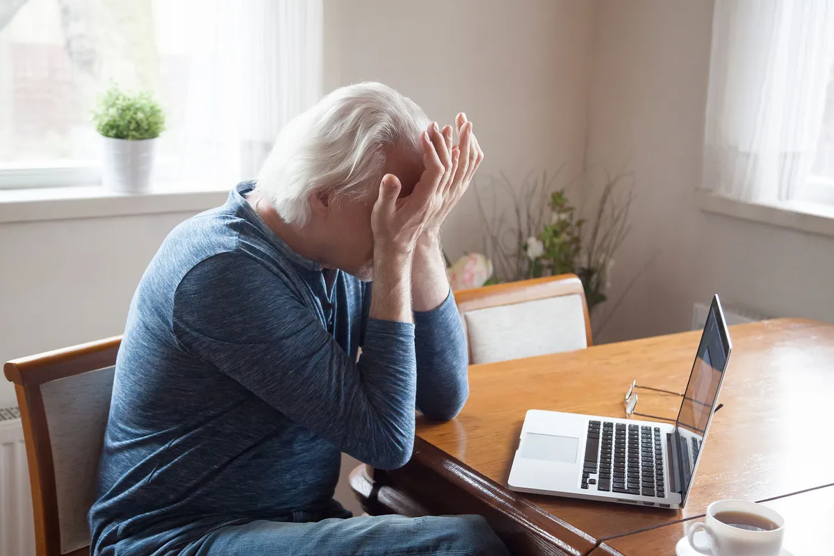 Tired aged man massaging eyes working too long at laptop, senior male feel exhausted suffer from headache after using computer, elderly having blurry vision or dizziness from pc screen