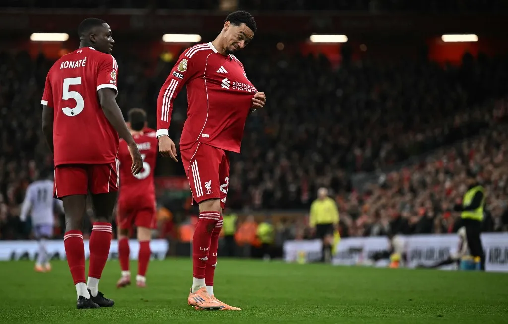 Liverpool's French striker #22 Hugo Ekitike (R) tugs at the emblem on his shirt as he celebrates scoring the team's second goal during the English Premier League football match between Liverpool and Brighton and Hove Albion at Anfield in Liverpool, north west England on December 13, 2025. (Photo by Paul ELLIS / AFP) / RESTRICTED TO EDITORIAL USE. No use with unauthorized audio, video, data, fixture lists, club/league logos or 'live' services. Online in-match use limited to 120 images. An additional 40 images may be used in extra time. No video emulation. Social media in-match use limited to 120 images. An additional 40 images may be used in extra time. No use in betting publications, games or single club/league/player publications. / 