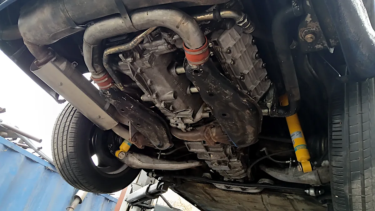 Egy autószervizben felemelt veteránkorú Porsche 911-es motorja alulról.