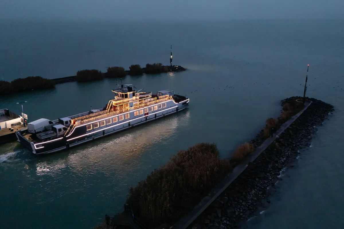 Szántód, 2025. december 3.
A drónnal készült felvételen ünnepi fényekkel díszített komp a Balatonon Szántódnál 2025. december 3-án. A „fénykomp” november utolsó hétvégéjétől 2026. január 31-ig közlekedik reggel 7:00-től 8:00-ig, az esti időszakban pedig 16:00 óra után.
MTI/Vasvári Tamás