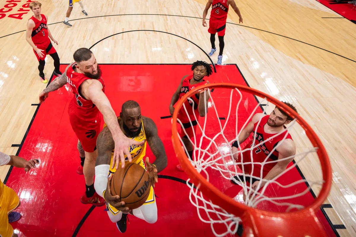 TORONTO, ON - DECEMBER 4: LeBron James #23 of the Los Angeles Lakers goes to the basket against Sandro Mamukelashvili #54 of the Toronto Raptors during second half action at Scotiabank Arena on December 4, 2025 in Toronto, Ontario, Canada. NOTE TO USER: User expressly acknowledges and agrees that, by downloading and/or using this Photograph, user is consenting to the terms and conditions of the Getty Images License Agreement.   Andrew Lahodynskyj/Getty Images/AFP (Photo by Andrew Lahodynskyj / GETTY IMAGES NORTH AMERICA / Getty Images via AFP)