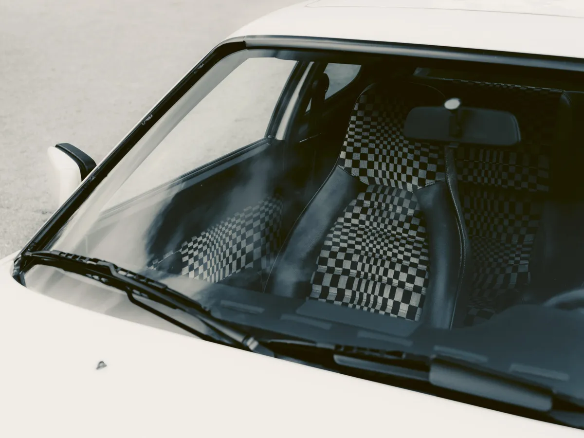 Egy Pasha szövetkárpittal behúzott ülés látszik egy Porsche szélvédőjén keresztül.