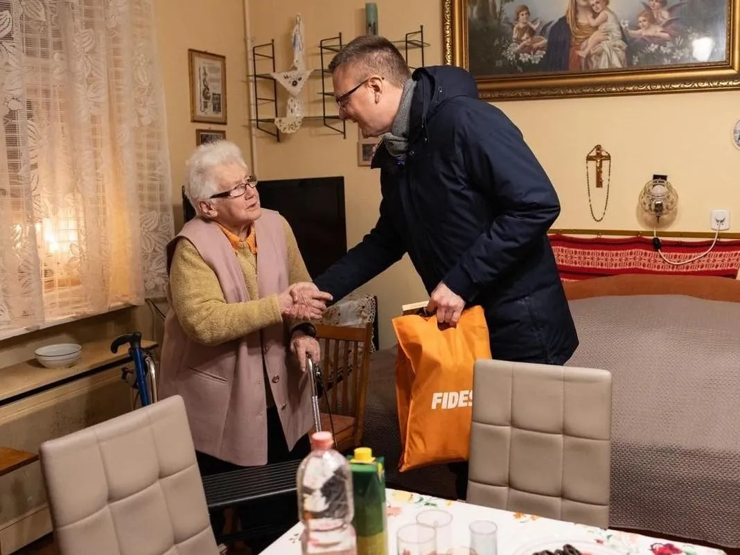Rétvári Bence, a BM parlamenti államtitkára segít egy idős hölgynek a boltban megvásárolt holmik hazajuttatásában (Forrás: Facebook/Rétvári Bence)