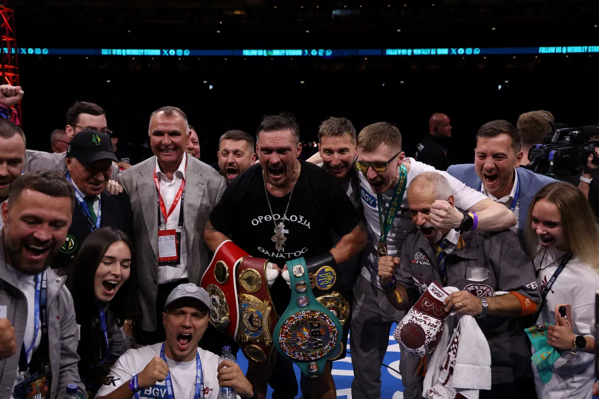 Ukraine's Oleksandr Usyk and his team celebrate defeating Britain's Daniel Dubois in their undisputed world heavyweight boxing title bout at Wembley Stadium in London on July 19, 2025. (Photo by Adrian Dennis / AFP)