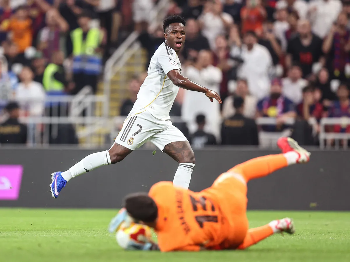 Real Madrid's Brazilian forward #07 Vinicius Junior reacts as Barcelona's Spanish goalkeeper #13 Joan Garcia catches the ball during the Spanish Super Cup final football match between FC Barcelona and Real Madrid at the King Abdullah Stadium in Jeddah on January 11, 2026. (Photo by Haitham AL-SHUKAIRI / AFP)