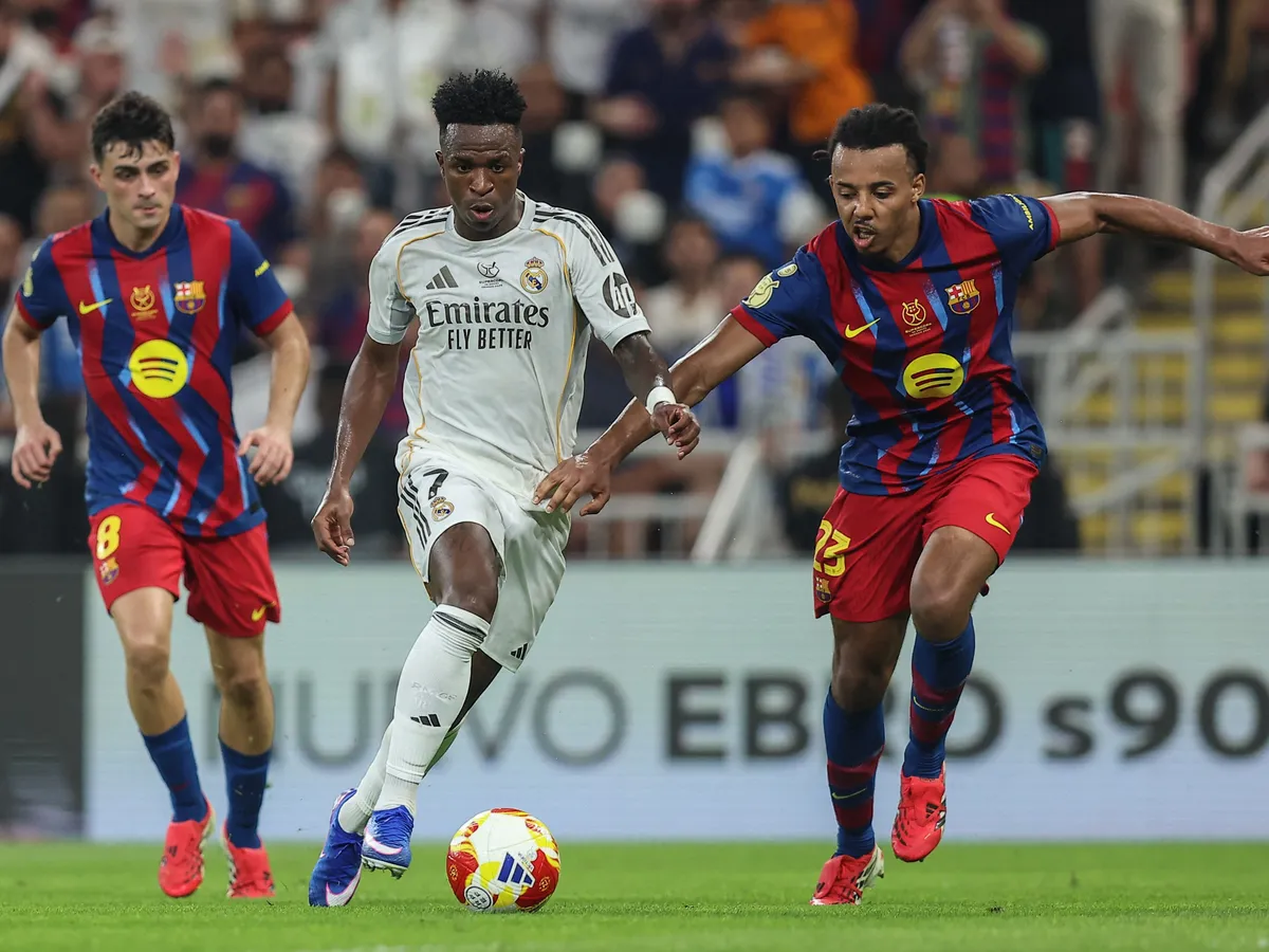 Real Madrid's Brazilian forward #07 Vinicius Junior and Barcelona's French defender #23 Jules Kounde fight for the ball during the Spanish Super Cup final football match between FC Barcelona and Real Madrid at the King Abdullah Stadium in Jeddah on January 11, 2026. (Photo by Haitham AL-SHUKAIRI / AFP)