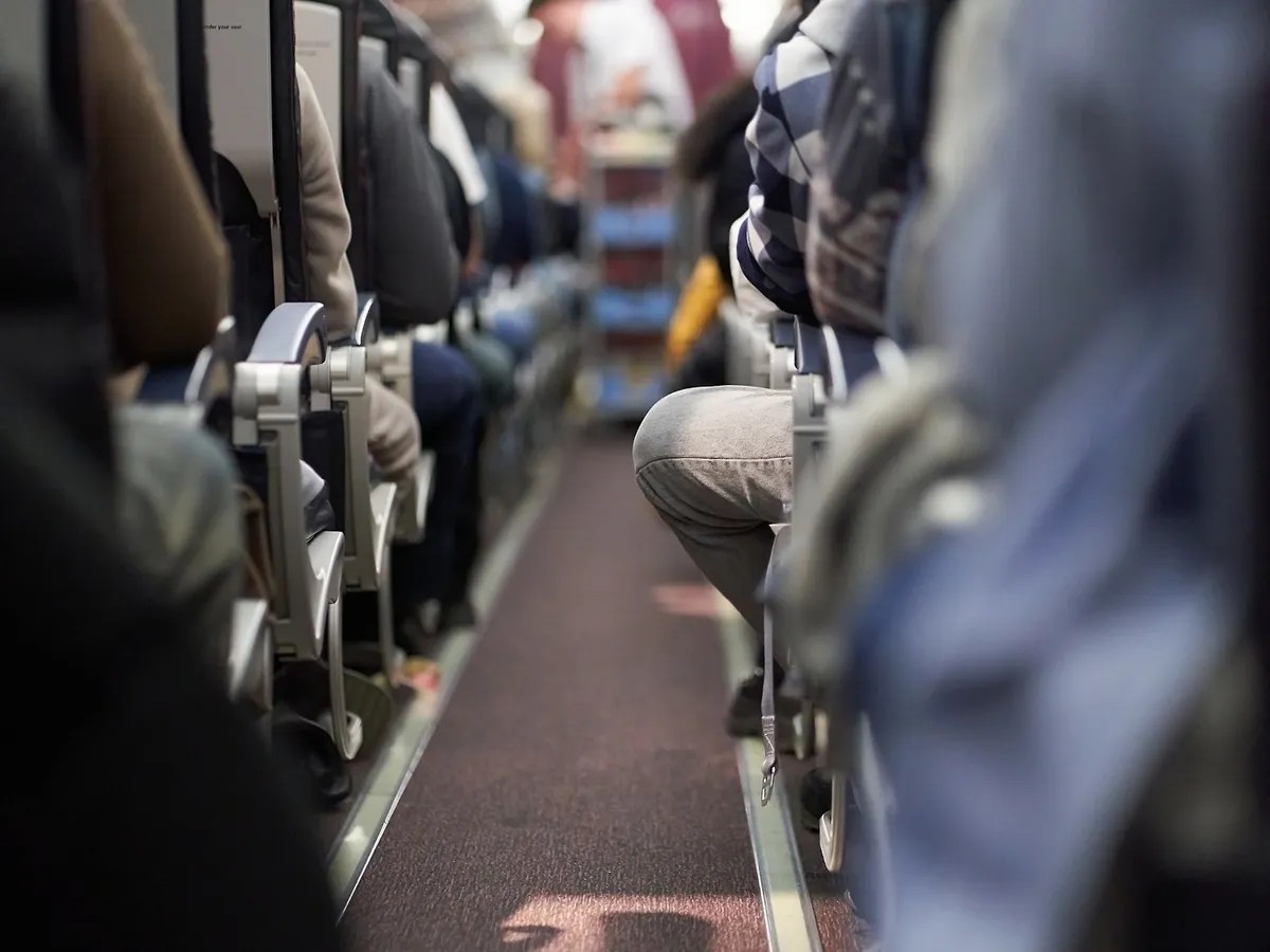 The interior of an airplane with passengers sitting on the seats. A male steward delivers food. Passengers sit along the row on the plane. The concept of travel. High quality photo