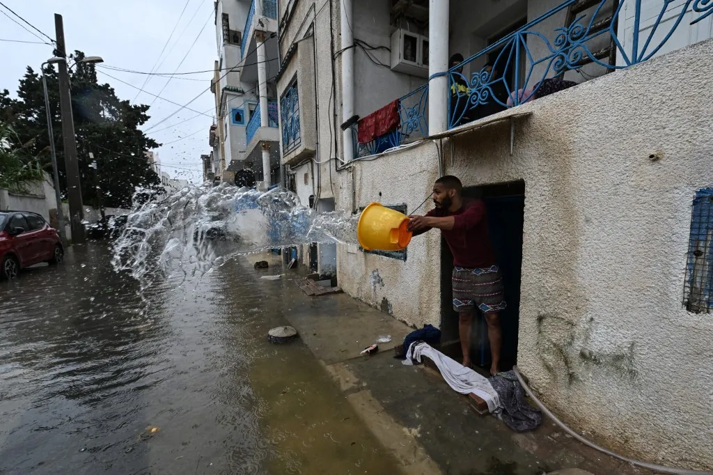 A man uses a bucket to remove flood water from his home, in La Goulette near the capital Tunis, on Januray 20, 2026. Flooding across Tunisia has killed three people, authorities said January 20, with one official reporting a "critical" situation as parts of the North African country experienced their heaviest rainfall in more than 70 years. (Photo by FETHI BELAID / AFP)