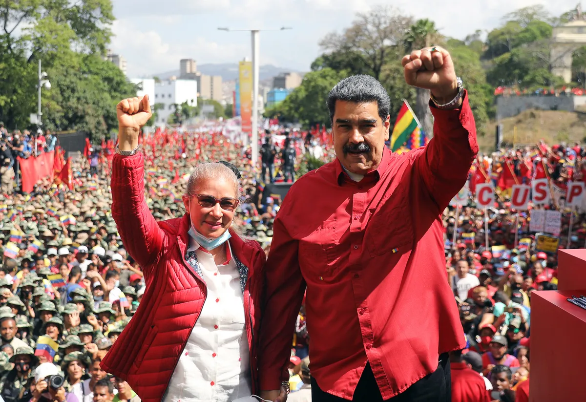 (FILES) Handout photo released by the Miraflores presidential palace press office showing Venezuela's President Nicolas Maduro (R) accompanied by his wife Cilia Flores raising their clenched fists during a civil-military parade to commemorate the 20th anniversary of the coup that briefly removed late Venezuelan president (1999-2013) Hugo Chavez from power, in Caracas on April 13, 2022. President Donald Trump said on January 3, 2026, that US forces had captured Venezuelan leader Nicolas Maduro after launching a "large scale strike" on the South American country. "The United States of America has successfully carried out a large scale strike against Venezuela and its leader, President Nicolas Maduro, who has been, along with his wife, captured and flown out of the Country," Trump said on Truth Social. (Photo by Venezuelan Presidency / AFP) / RESTRICTED TO EDITORIAL USE-MANDATORY CREDIT - AFP PHOTO / VENEZUELAN PRESIDENCY - NO MAFRKETING - NO ADVERTISING CAMPAIGNS - DISTRIBUTED AS A SERVICE TO CLIENTS