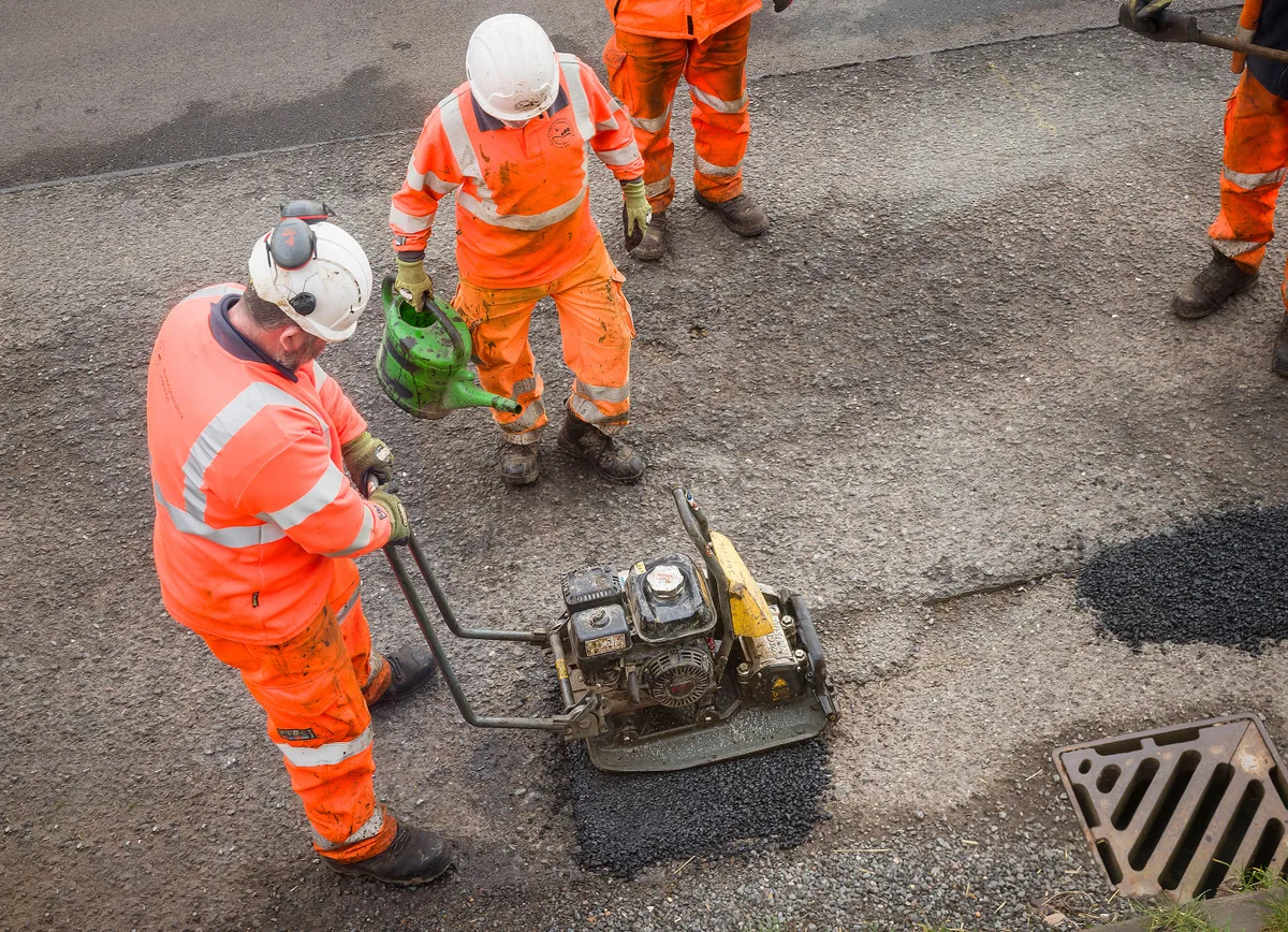 BUCKINGHAMSHIRE, UK - March 19, 2024. Road workers repairing potholes. Temporary pothole patch repairs on a country road in disrepair., Megfeszített tempóban kátyúznak a Magyar Közút munkatársai a hideg tél után